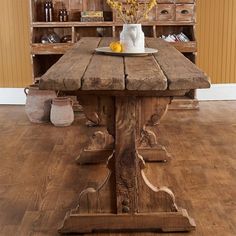 a wooden table topped with a white vase filled with flowers next to an old dresser