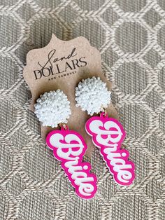 two pink and white earrings with the word barbie on them