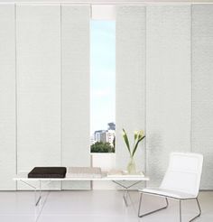 an empty room with two white chairs and a table in front of a large window