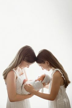 Two older sisters holding their newborn baby sister.  The newborn is wrapped in white with a knitted bonnet.  Older siblings are wearing white dresses with long brown hair on a white background. Newborn Photography Older Siblings, Newborn Family Photos Older Sibling, Newborn And Teenage Sibling Photo Ideas, Newborn Photos With Siblings Sisters, Newborn Session With Older Siblings, Older Siblings With Newborn, Newborn Photography With Older Siblings, Newborn Pictures With Older Siblings