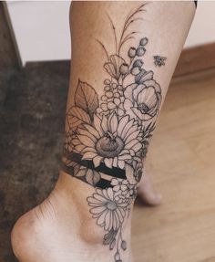 a woman's foot with flowers and leaves on the bottom part of her leg