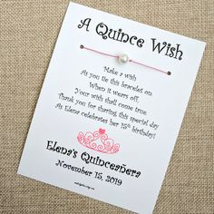 a quince wish card with a pink string attached to it on a piece of fabric