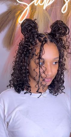 a young woman with curly hair wearing a white shirt and an afro style bun in front of a neon sign that says sugars