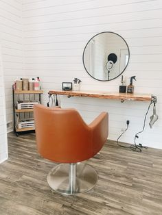 an orange chair sitting in front of a mirror on top of a wooden table next to a shelf