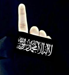 the hand is pointing at something that appears to be in an arabic language on a black background