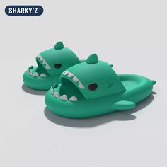 a pair of green slippers with shark teeth on the front and back, sitting next to each other