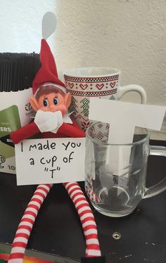 an elf is holding a sign that says i made you a cup of tea in it