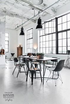 an industrial style dining room with large windows and black chairs in front of the table