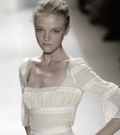 a woman in a white dress is walking down the runway