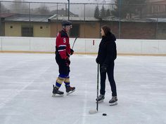 two people standing on an ice rink holding hockey sticks