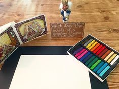 a wooden table topped with lots of different colored crayons next to a white board