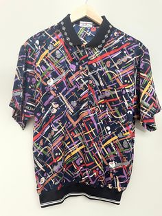 "American made menswear great casual Friday shirt for hime, perfect for valentine day gift birthday or fatherly gift.  Sytlish modern this will great on that special man in your life.Will look great on him in either linen pants or jeans. this chic and timeless pattern is for that man who enjoys turning heads. Made in the 🇺🇸 USA by Statel Horse  This shirt is large medium and it is in pristine condition. Size chest 44\"	in stock	64.85 USD	"	0.00 USD	Clothing > Men's Clothing > Shirts & Tees > D Retro Short Sleeve Polo Shirt For Spring, Multicolor Polo Collar Top With Graphic Print, Multicolor Graphic Print Polo Collar Top, Multicolor Graphic Print Top With Polo Collar, Multicolor Graphic Print Short Sleeve Polo Shirt, Purple Collared Top With Graphic Print, Multicolor Cotton Top With Collared Neckline, Retro Multicolor Collared T-shirt, Retro Graphic Print Polo Collar Tops