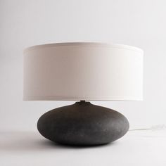 a table lamp with a white shade on it and a cord plugged into the base