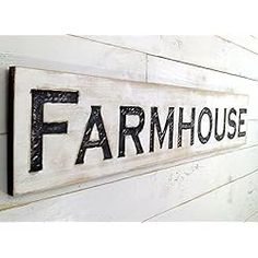 a sign on the side of a building that says farmhouse and is hanging on the wall