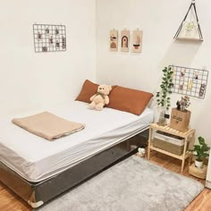 a bed with a teddy bear sitting on top of it next to a wooden table