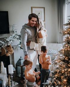 a man, woman and two children standing in front of a christmas tree