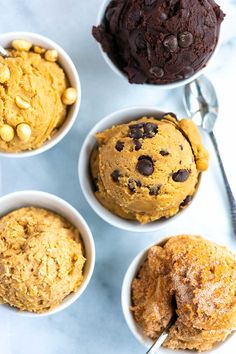 four bowls filled with ice cream and chocolate chip cookies on top of a marble counter