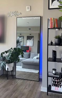 a mirror sitting on top of a wooden floor next to a shelf filled with plants