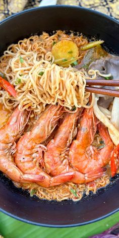 a bowl filled with noodles and shrimp on top of a table