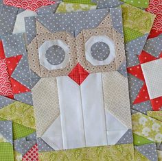 an owl made out of fabric sitting on top of a piece of quilted material