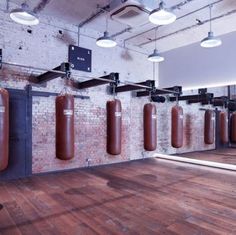 an empty gym with punching bags hanging from the ceiling and lights on either side of the wall