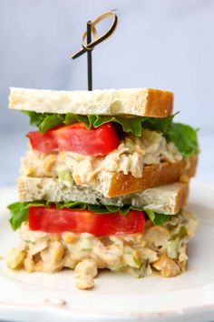 two sandwiches stacked on top of each other with tomatoes, lettuce and chicken