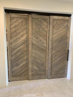 two wooden doors in the middle of a room with tile flooring and white walls