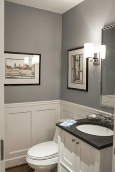 a bathroom with a sink, mirror and pictures on the wall