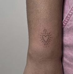 a person with a small tattoo on their arm that has a heart and sun in the middle