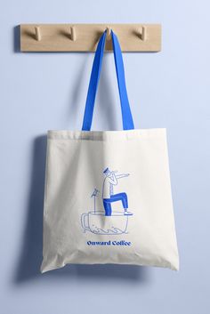 a tote bag hanging from a hook on a blue wall with the words onward coffee printed on it