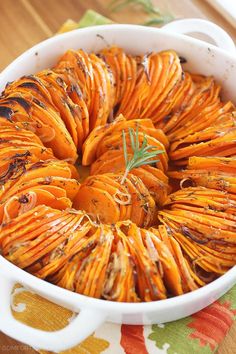 a casserole dish filled with cooked carrots and herbs on a colorful table cloth