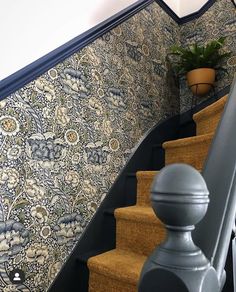 the stairs are decorated with an intricate wallpaper and potted plant next to them