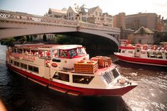 two red and white boats traveling under a bridge