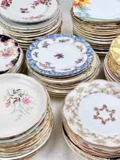 many plates are stacked on top of each other in different colors and designs, all with gold rims