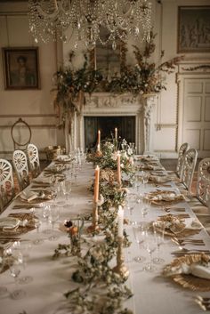 a long table is set with candles and place settings for an elegant dinner party in front of a fireplace