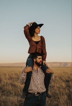 a man carrying a woman on his back in the middle of an open field with tall grass