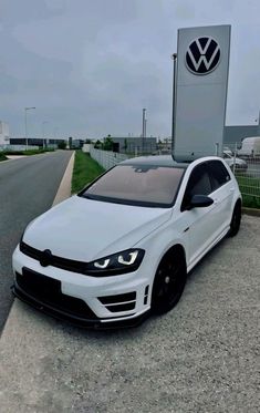 a white volkswagen car parked in front of a sign