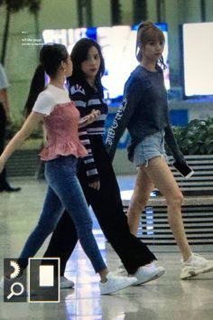 three girls are walking through an airport terminal