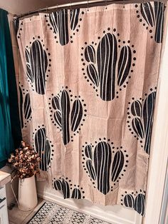 a shower curtain with black and white designs on it, next to a toilet in a bathroom