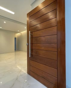 a modern wooden door in the middle of an empty room with white marble flooring