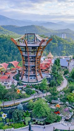 an aerial view of a park with many trees and mountains in the background