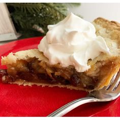 a piece of pie on a red plate with a fork and christmas tree in the background