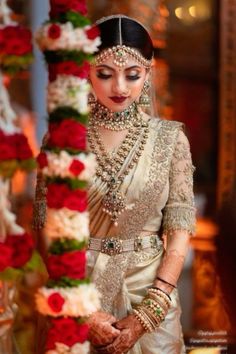 a woman in a wedding outfit standing next to a flower display with red roses on it