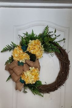 a wreath with yellow flowers and greenery hangs on a door