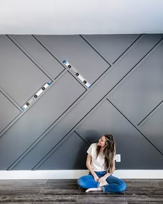 a woman sitting on the floor in front of a wall with arrows flying above her