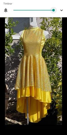 a yellow dress is on display in front of some bushes