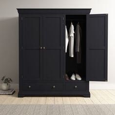 an image of a black wardrobe with clothes hanging on the door and shoes in it