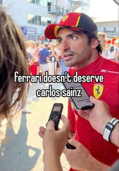 a man holding two cell phones in his hand and another person looking at them with the caption ferrari doesn't deserve carlos saintz