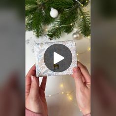 someone is holding up a christmas present in front of a tree