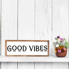 a sign that says good vibes next to a potted plant on a shelf